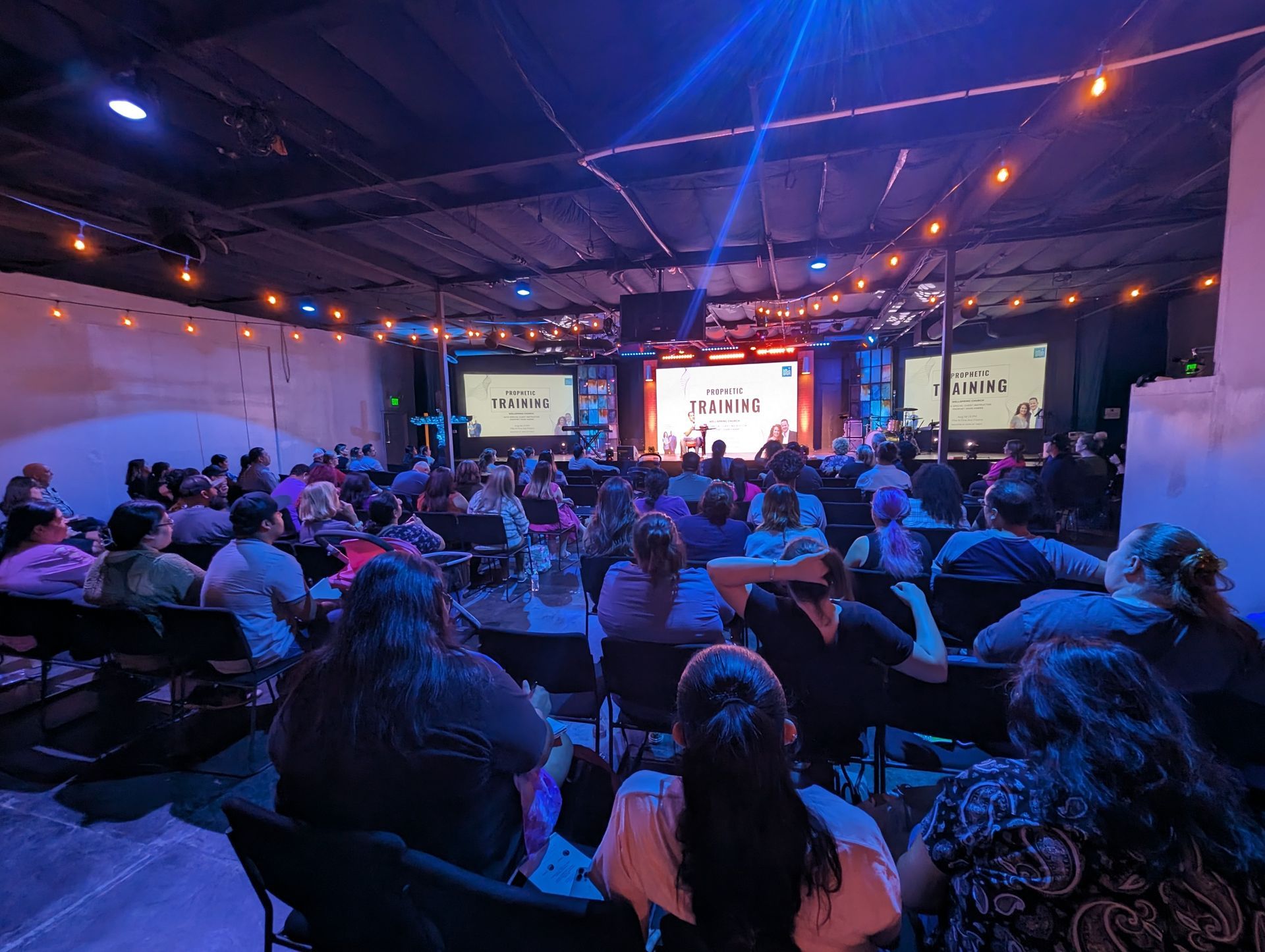 a large group of people are sitting in chairs in front of a stage .