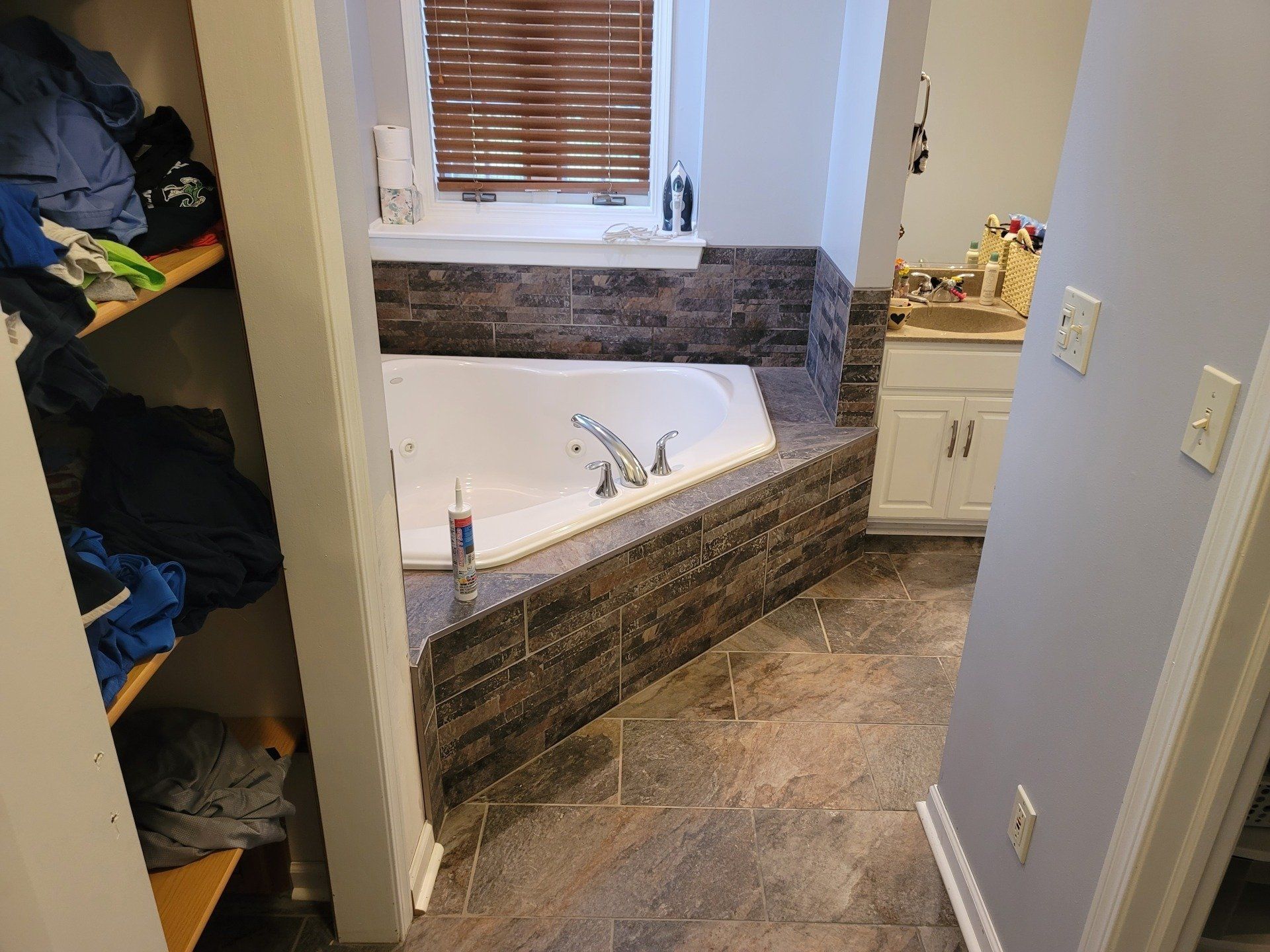 Bathroom with a built-in, tiled whirlpool tub. A closet is on the left, vanity on the right.