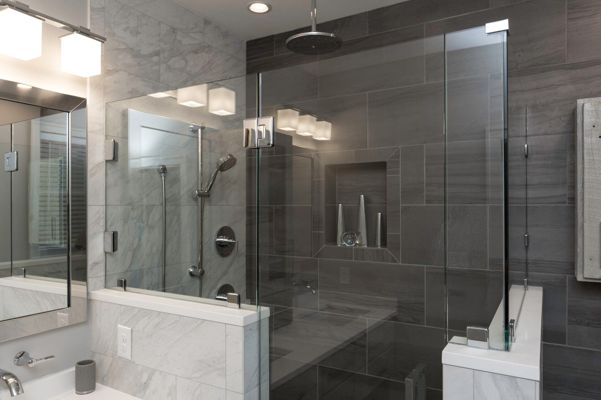 Modern bathroom with a glass shower, marble walls, and gray tile.