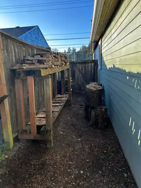 A wooden bench is sitting in the backyard of a house next to a fence.