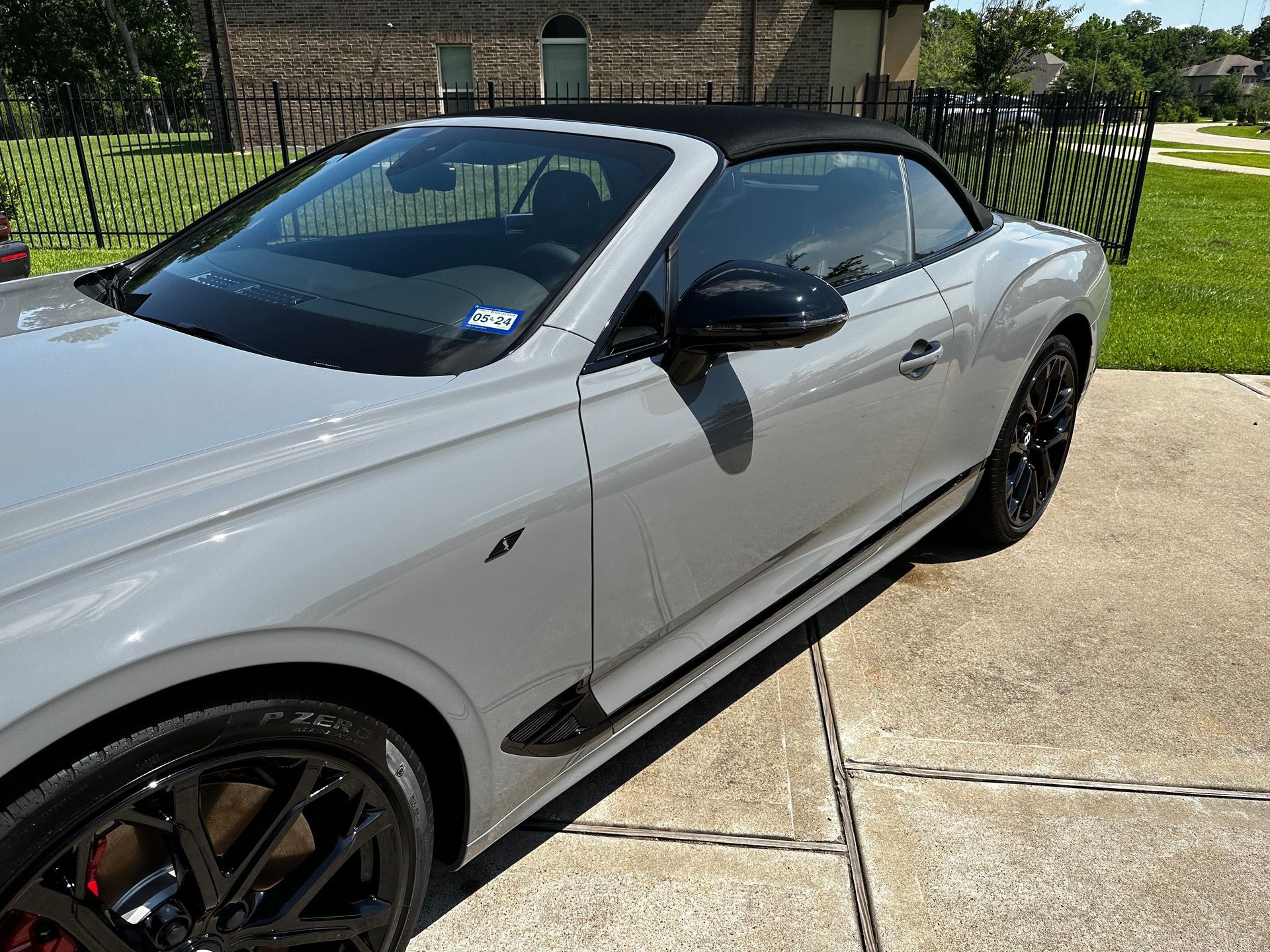A white sports car with a black top is parked in a driveway.