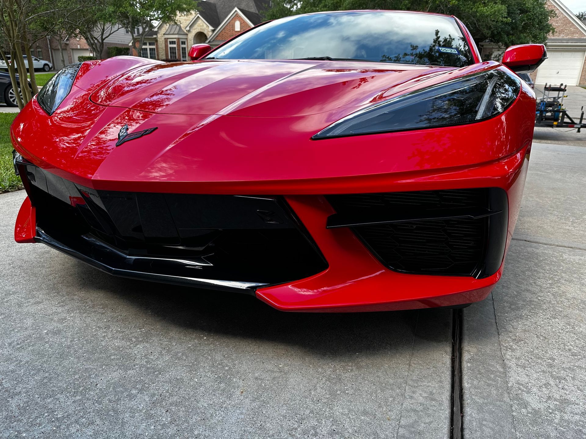 A red sports car is parked in a driveway in front of a house.
