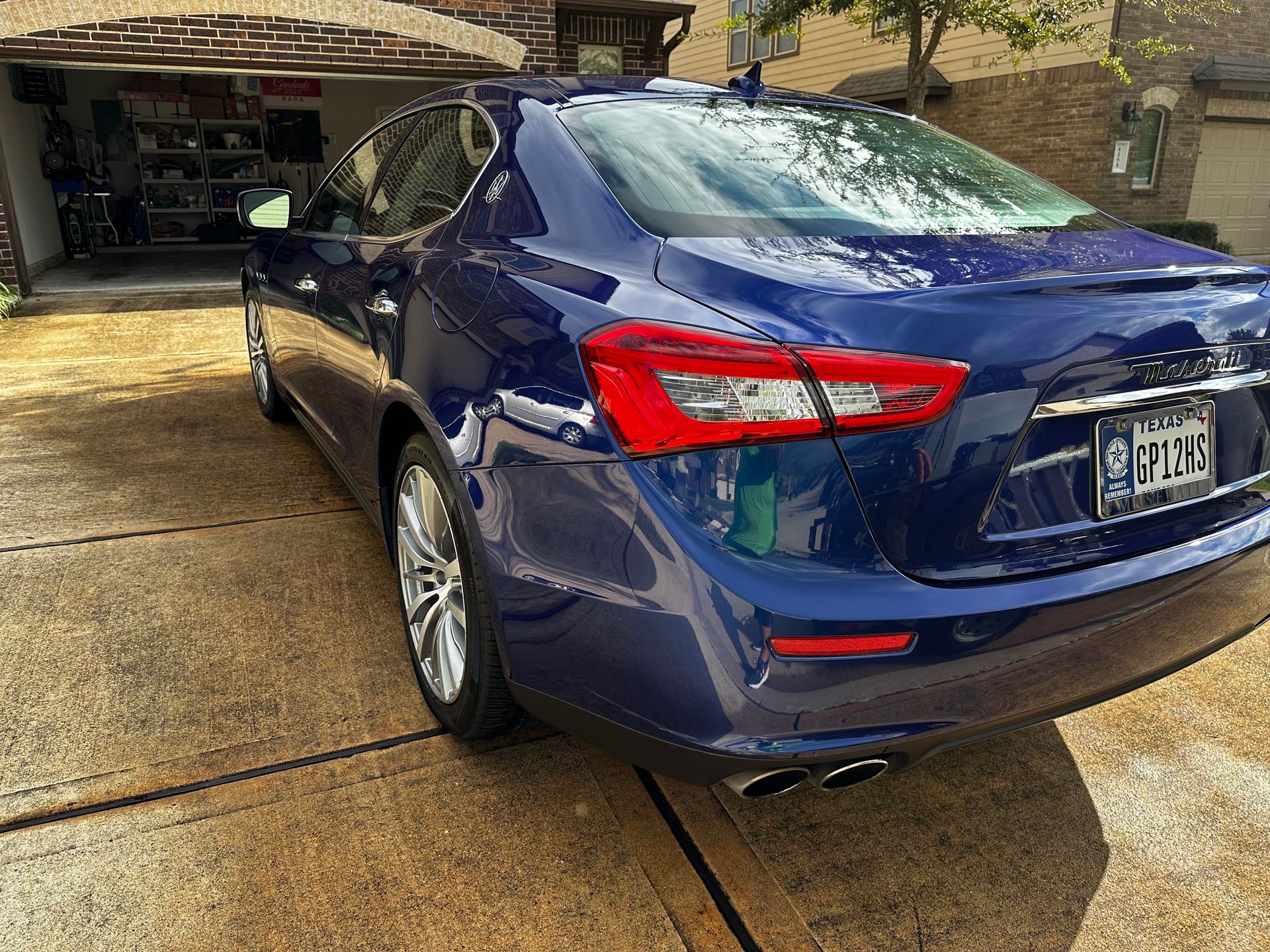 A blue car is parked in a driveway in front of a garage.