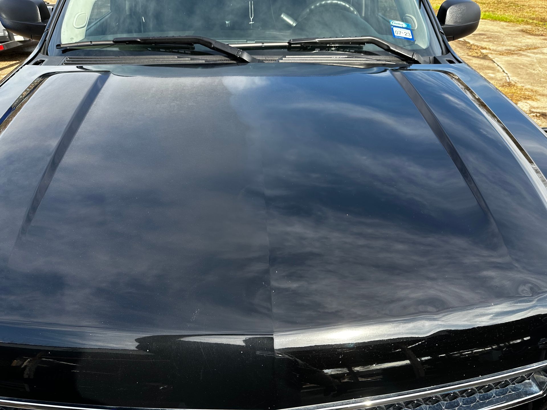 A black car with the hood up is parked in a field