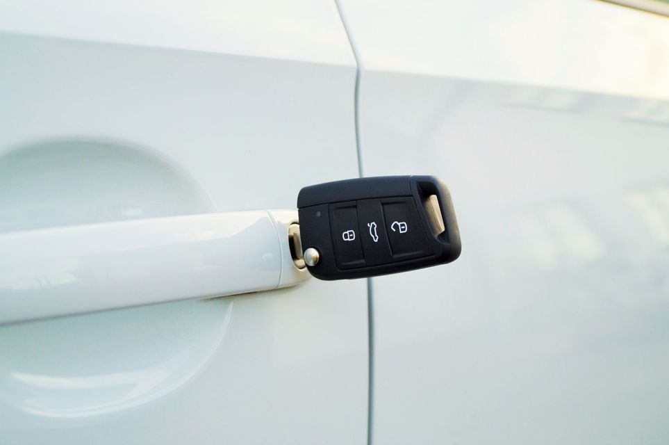 Llave de automóvil con control remoto junto a la puerta de un vehículo.