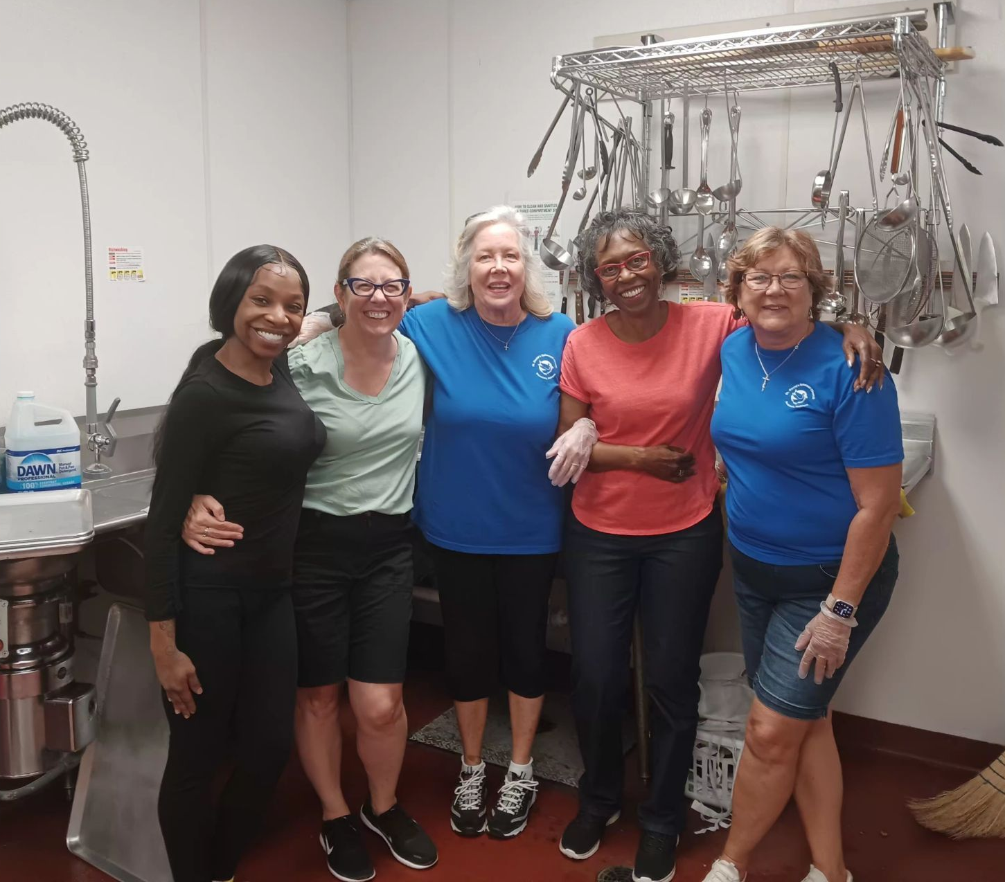 Group of 5 ladies volunteering at soup kitchen, doing dishes.