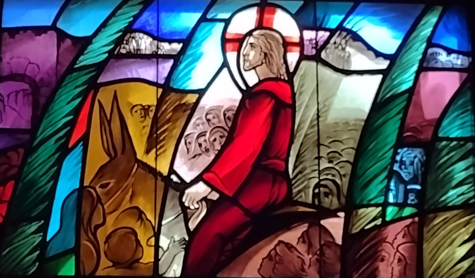 Stained glass window of Palms. Featuring Jesus on a donkey.