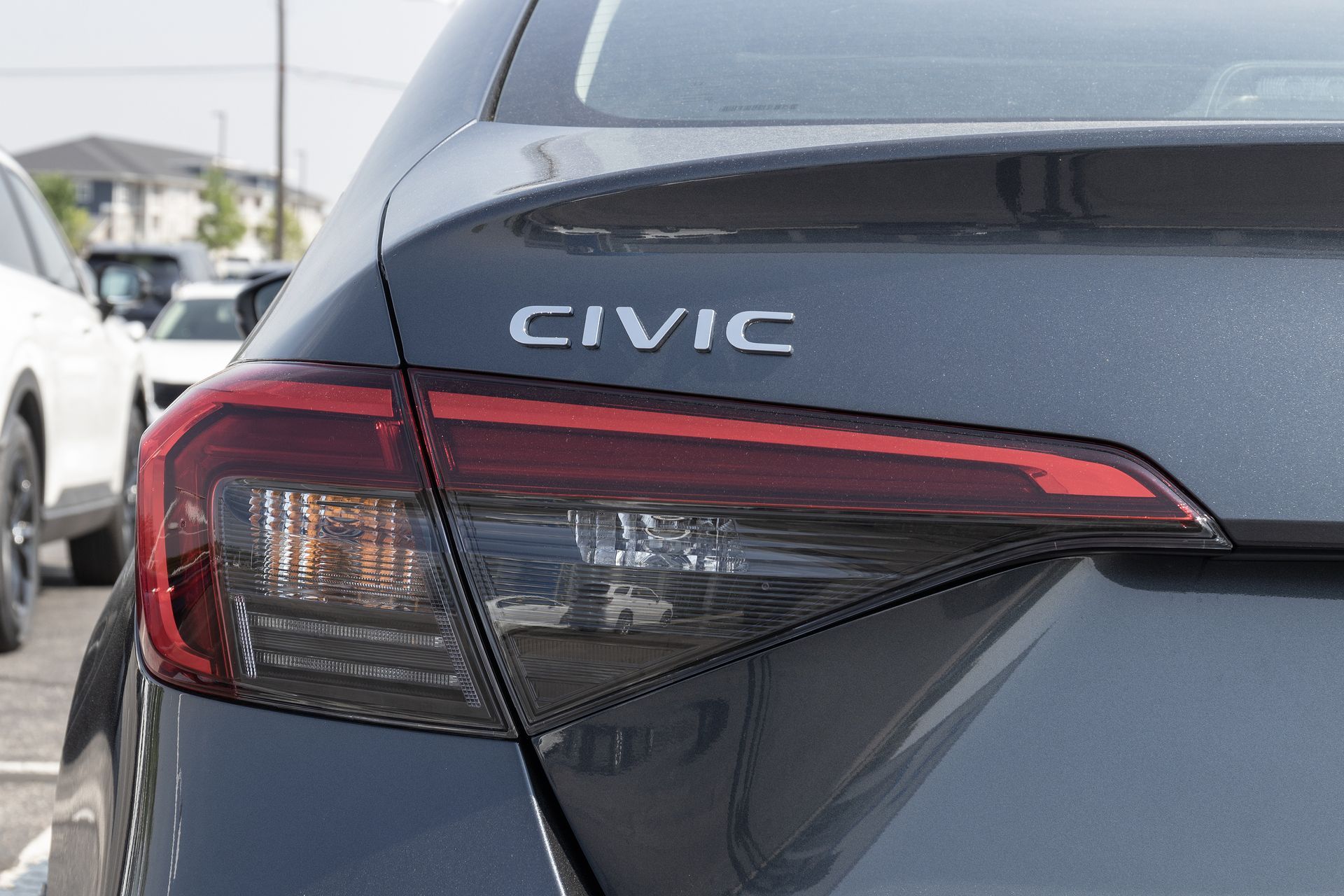 Close-up of a gray Honda Civic's rear. Tail light with red and amber lights, and