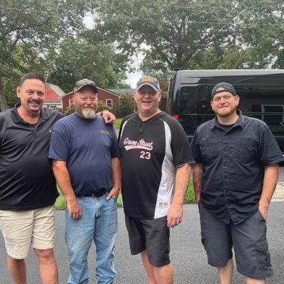a group of men are posing for a picture in front of a van .