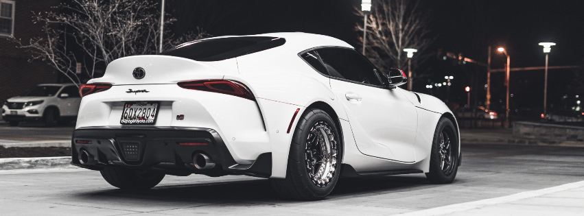 a white sports car is parked in a parking lot at night .