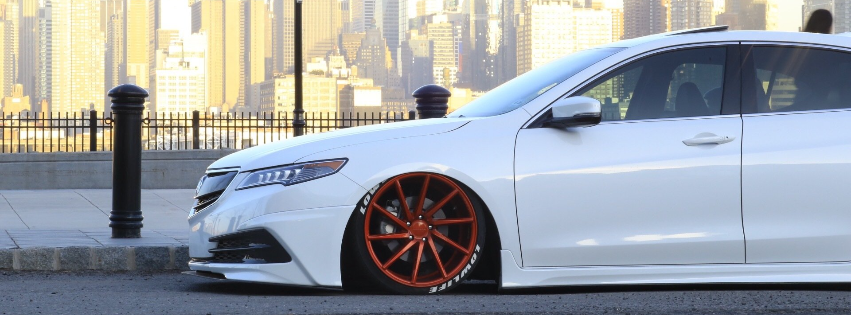 a white car with red wheels is parked on the side of the road .