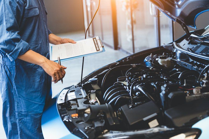 a mechanic is checking the engine of a car in a garage .