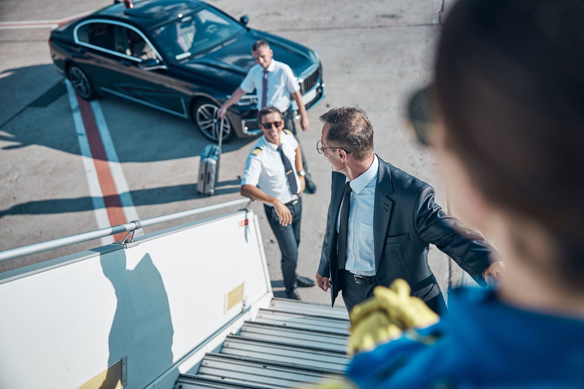 People boarding a private jet beside a black luxury car on the tarmac
