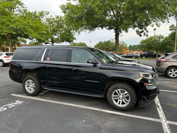 Black SUV parked in a lot under trees on an overcast day
