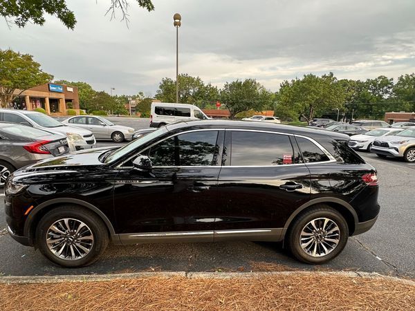 Black SUV parked in a lot under cloudy skies, side view.