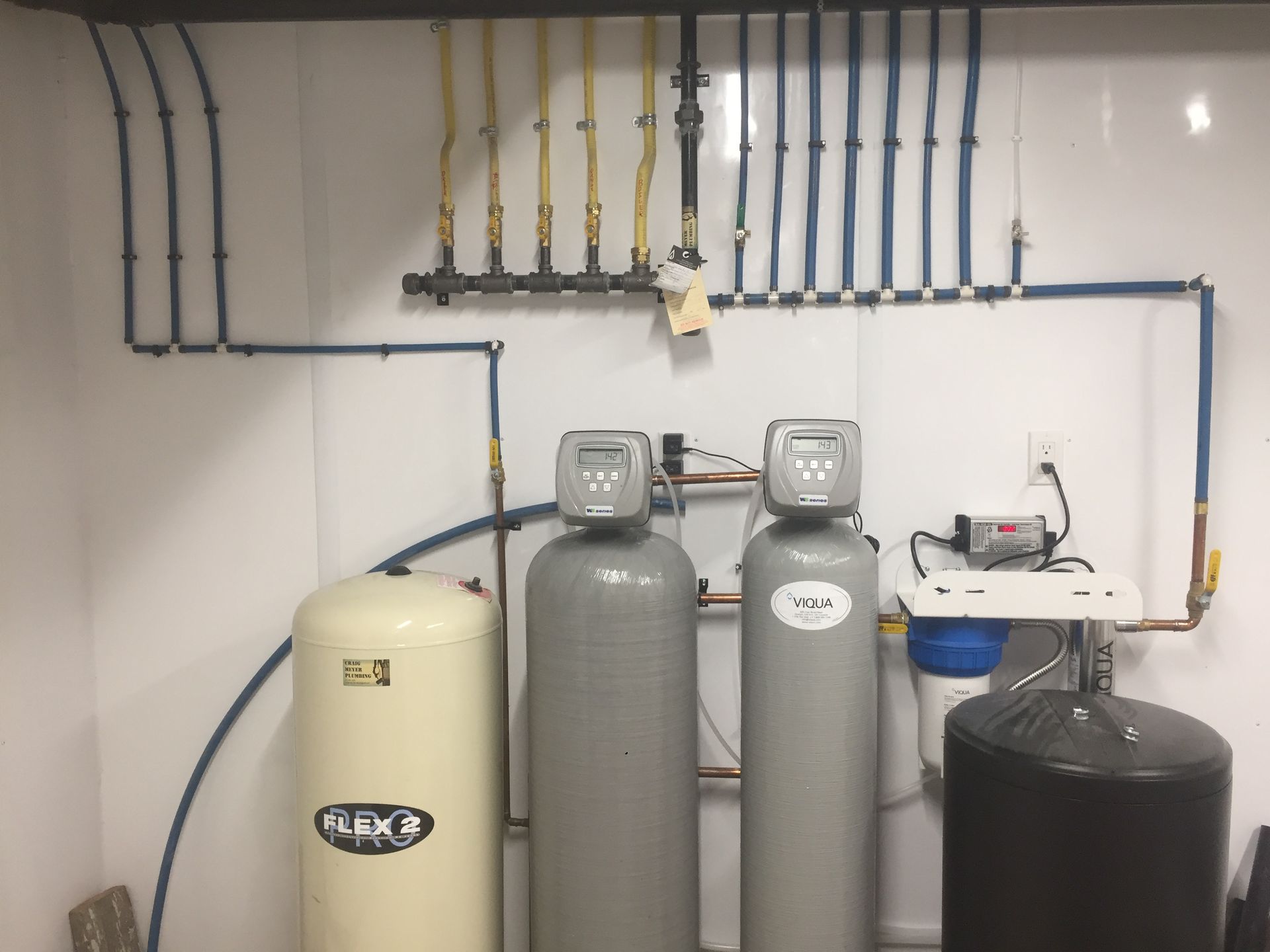 Water filtration and treatment system with blue and yellow pipes, and tanks.