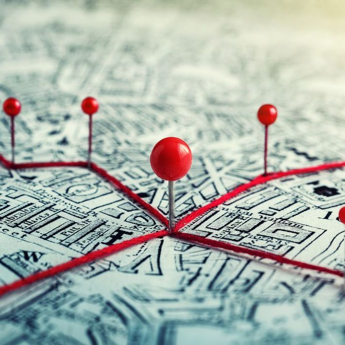 A map with red push pins and string connecting them, tracing a route.