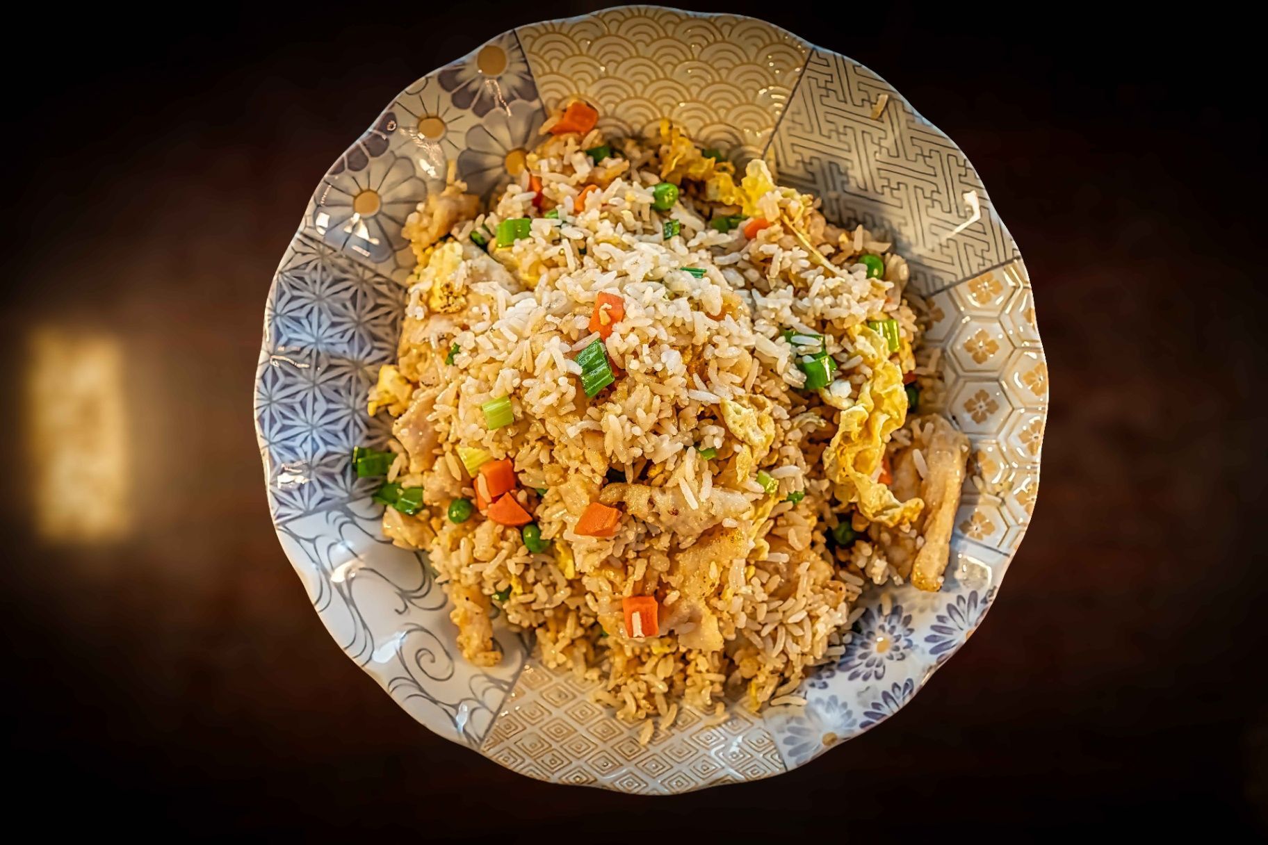 Plate of fried rice with peas and carrots on a decorative white dish