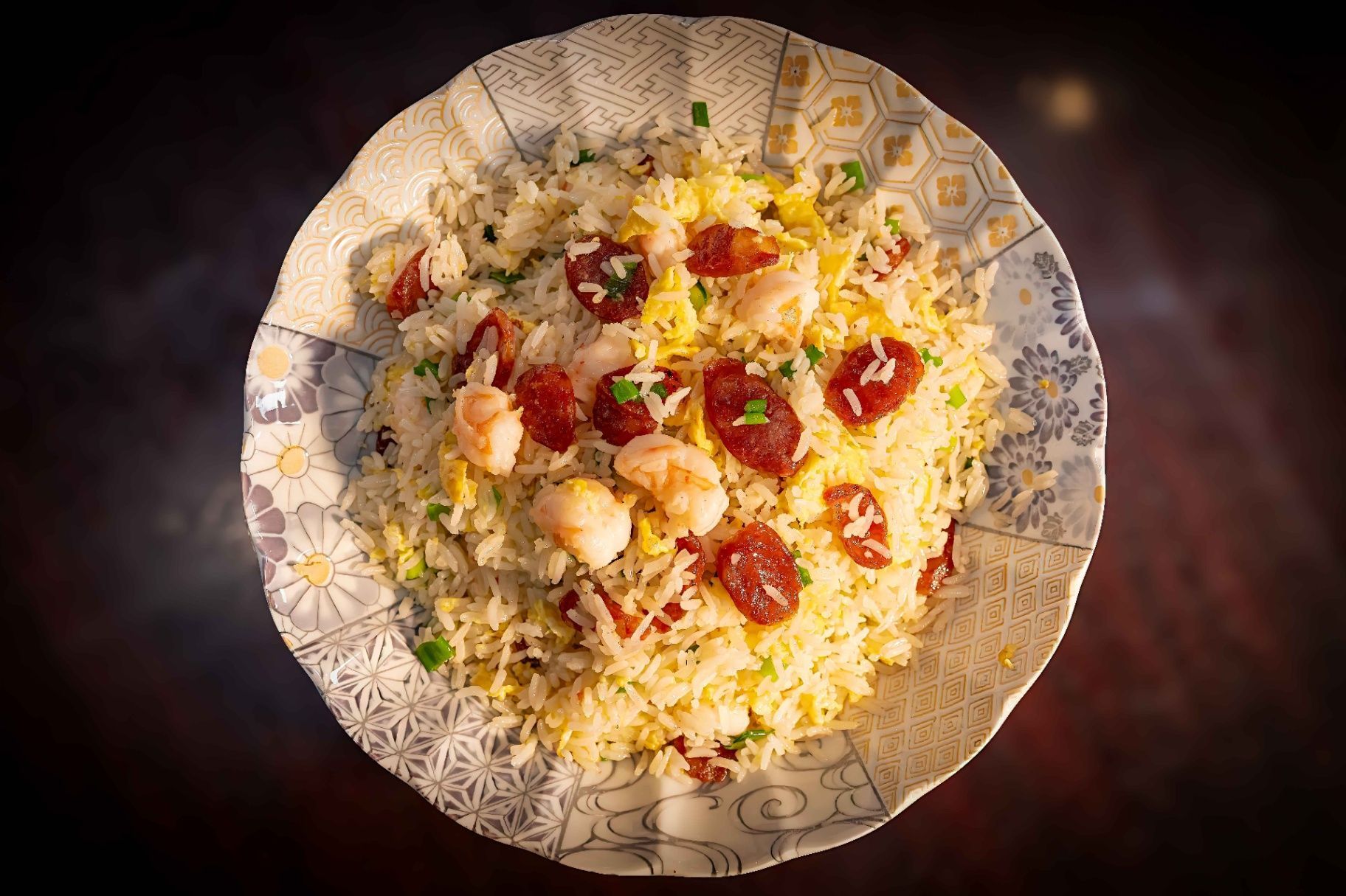 Top-down view of a bowl of rice topped with cherry tomatoes and herbs on a patterned plate