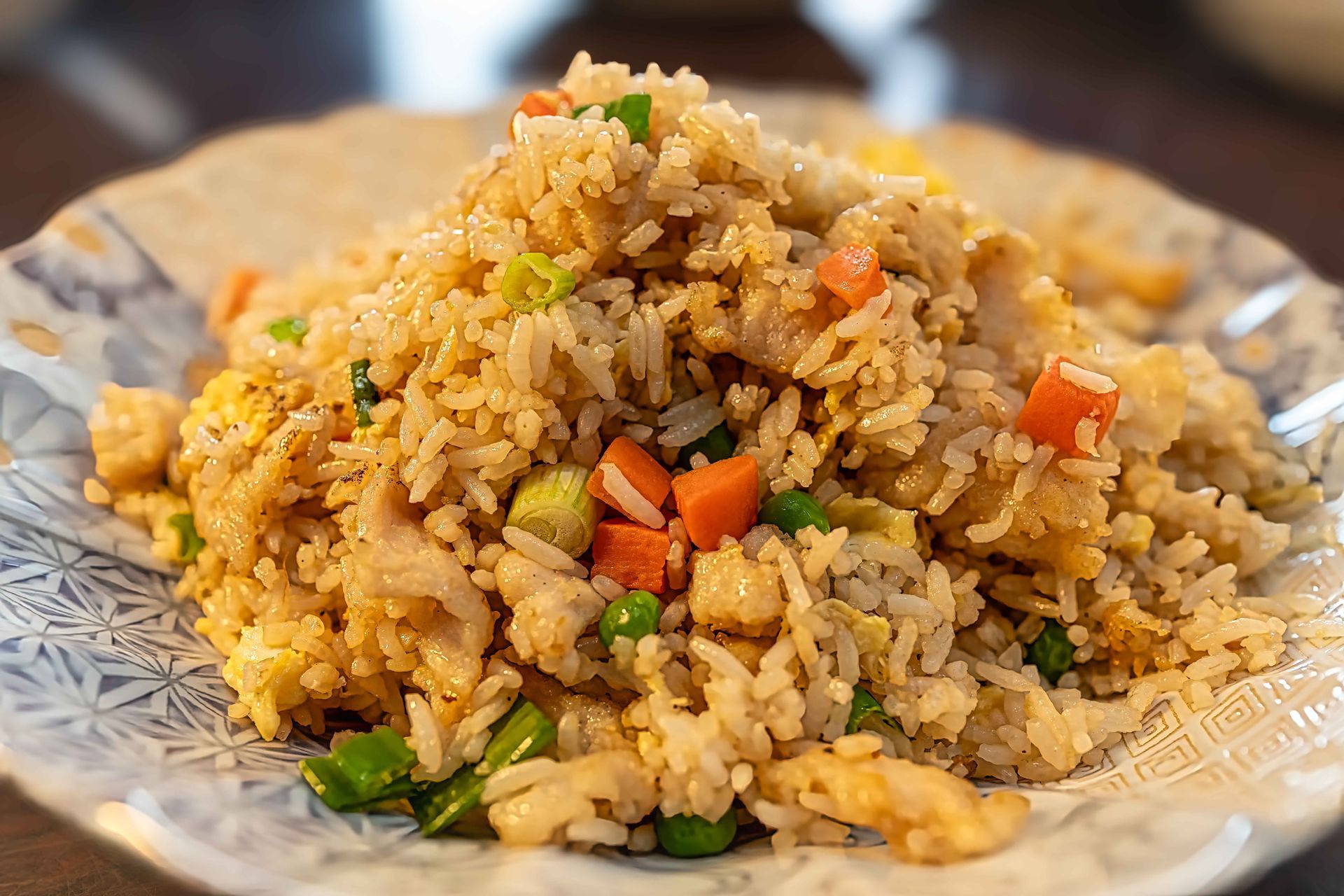 Plate of fried rice with mixed vegetables on a white floral plate