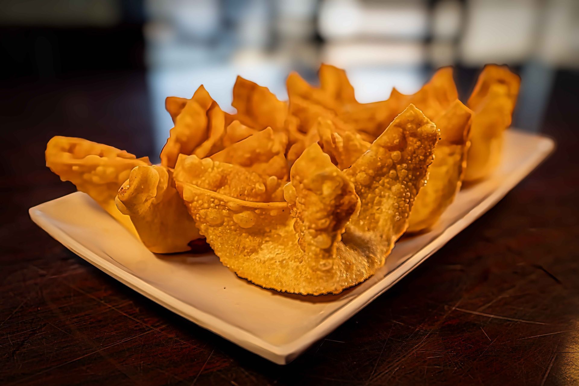 Plate of crispy fried wonton chips on a dark wooden table