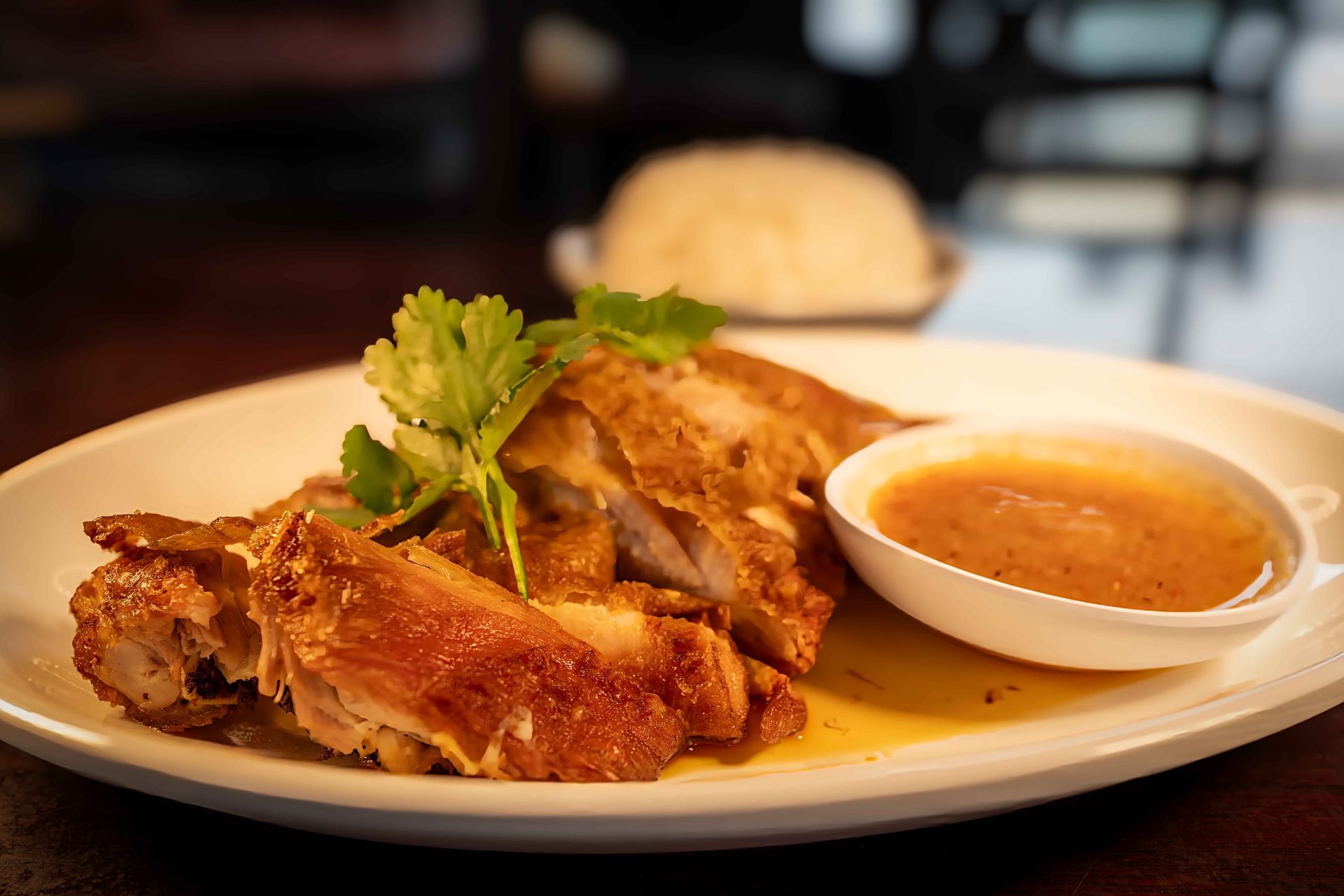 Golden fried chicken on a plate with dipping sauce and garnish in a restaurant setting