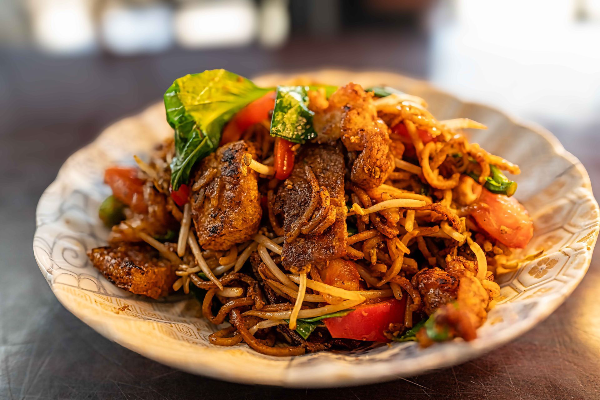 Plate of stir-fried noodles with vegetables and herbs, served on a white dish