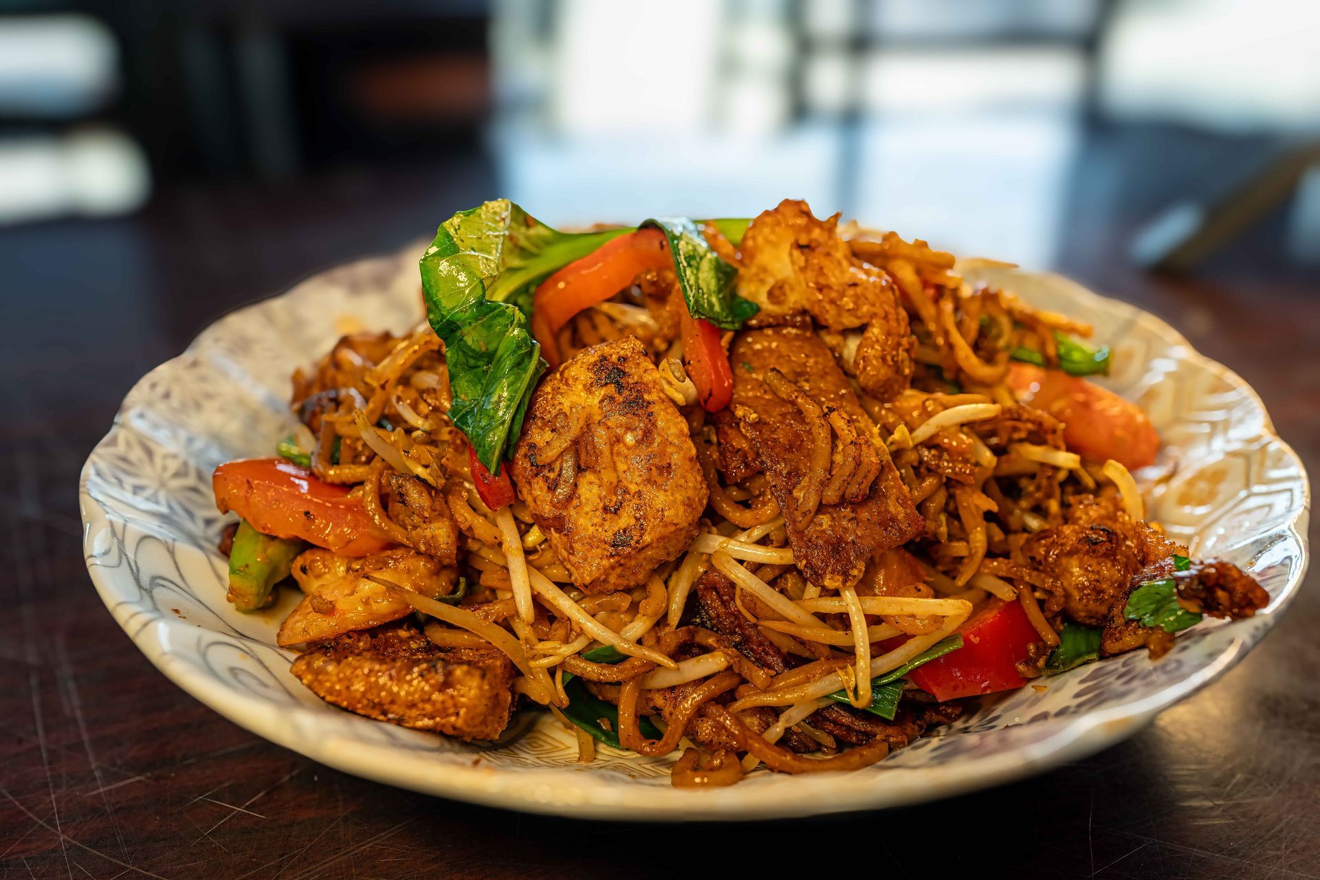 Plate of stir-fried noodles with vegetables and chicken on a table