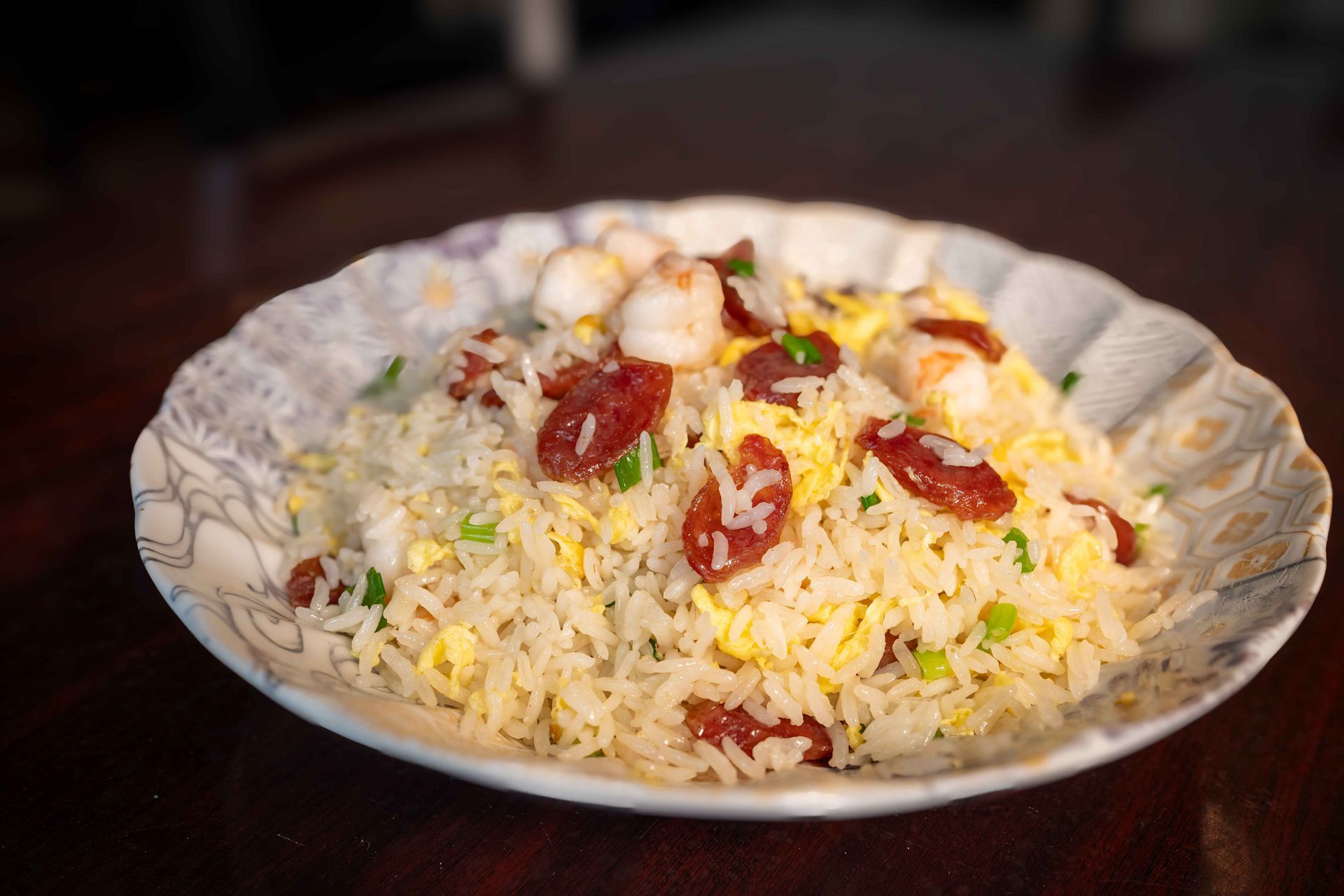 Plate of rice topped with red garnishes and herbs on a dark table