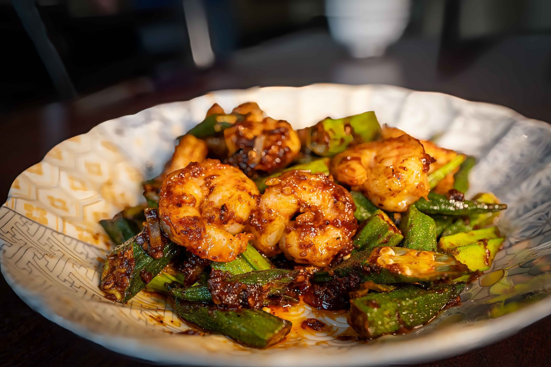 Plated spicy grilled shrimp with green vegetables in a patterned bowl