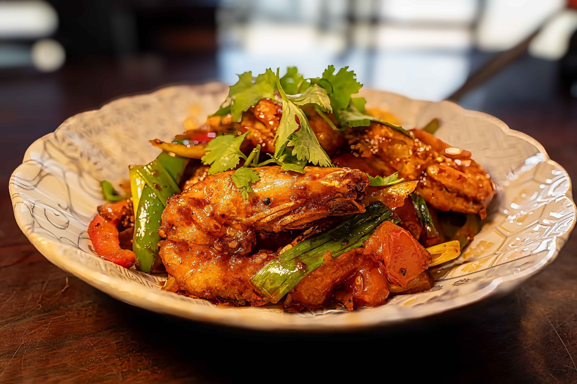 Spicy glazed chicken stir-fry garnished with cilantro on a decorative plate
