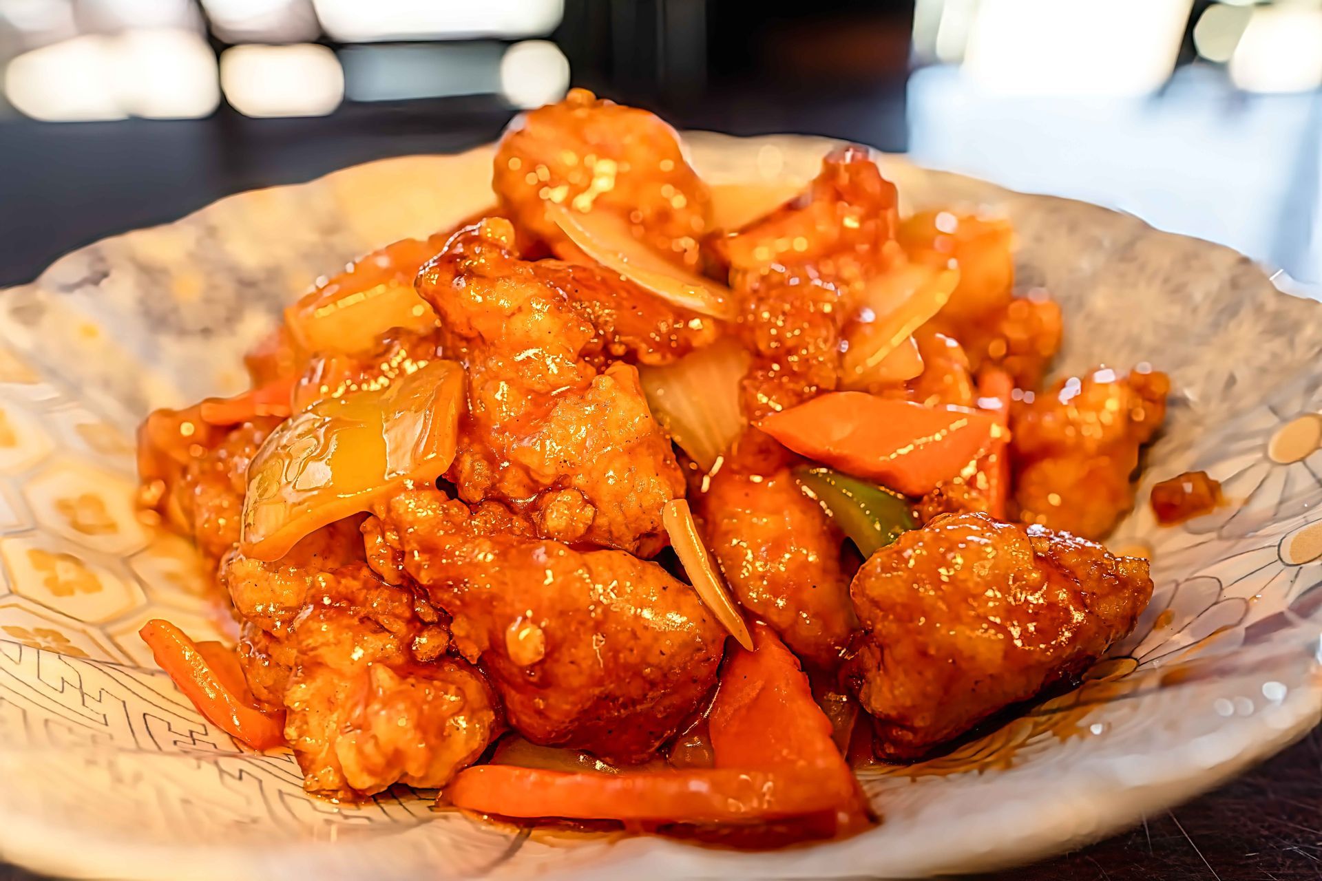 Orange sauced fried chicken pieces in a decorative bowl on a table