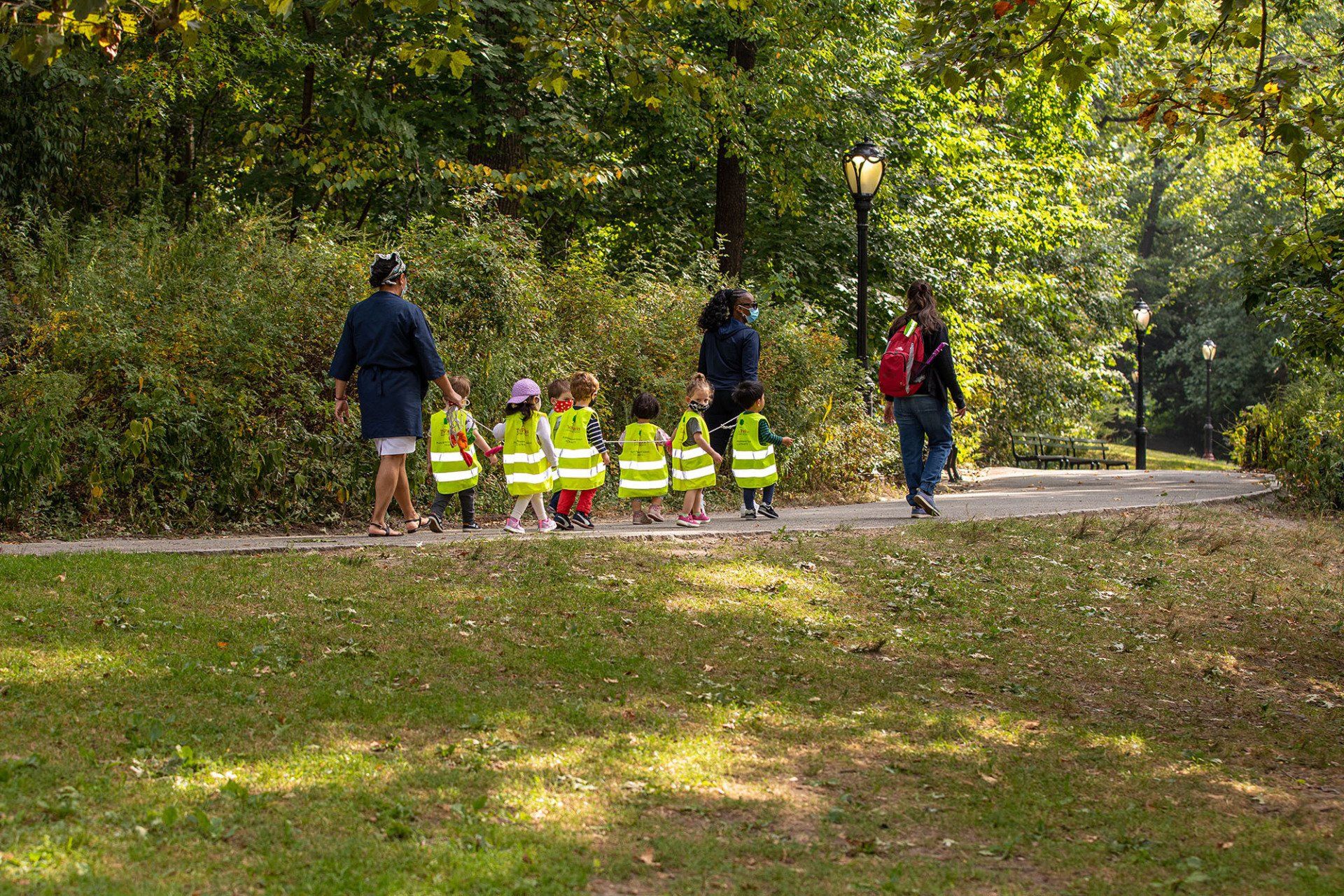 A group of children are walking down a path in a park.