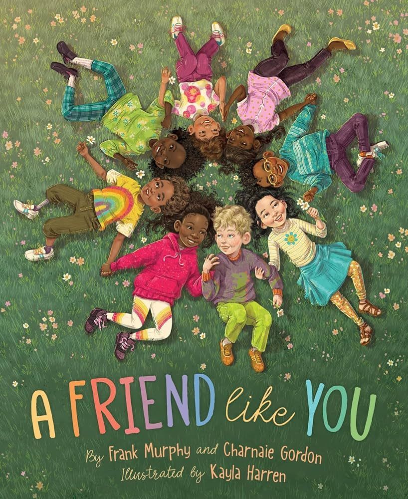 Group of diverse children laying in a circle on grass. Title