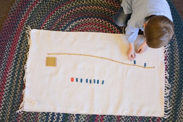 Child writing on a large paper with colored marks and a curved line on the floor