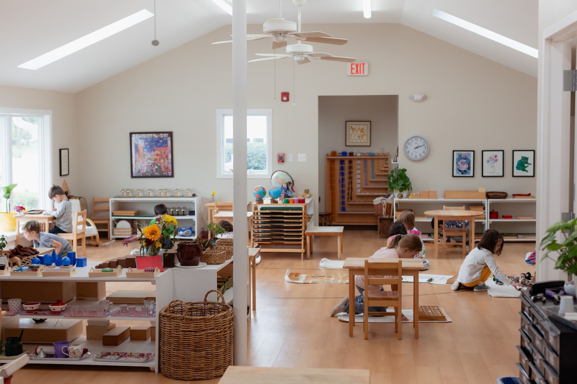 Bright classroom with children at tables, bookshelves, and colorful art on the walls