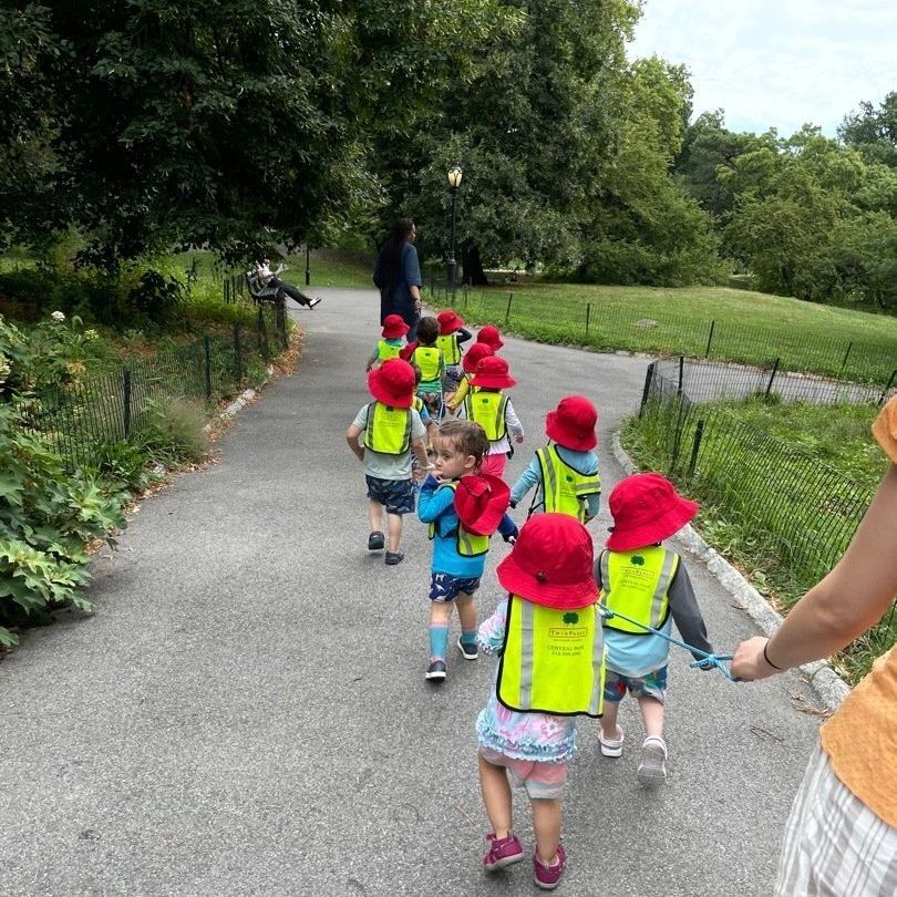 A group of children are walking down a path in a park.