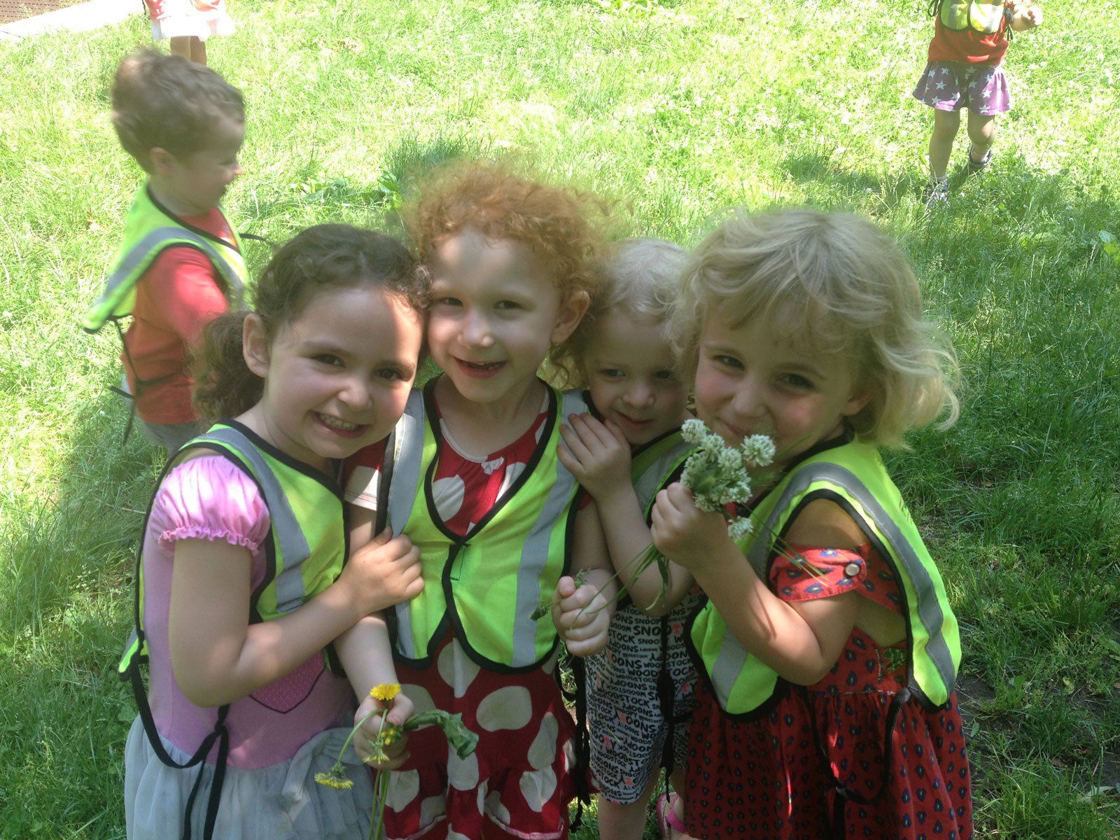 A group of children wearing safety vests are posing for a picture