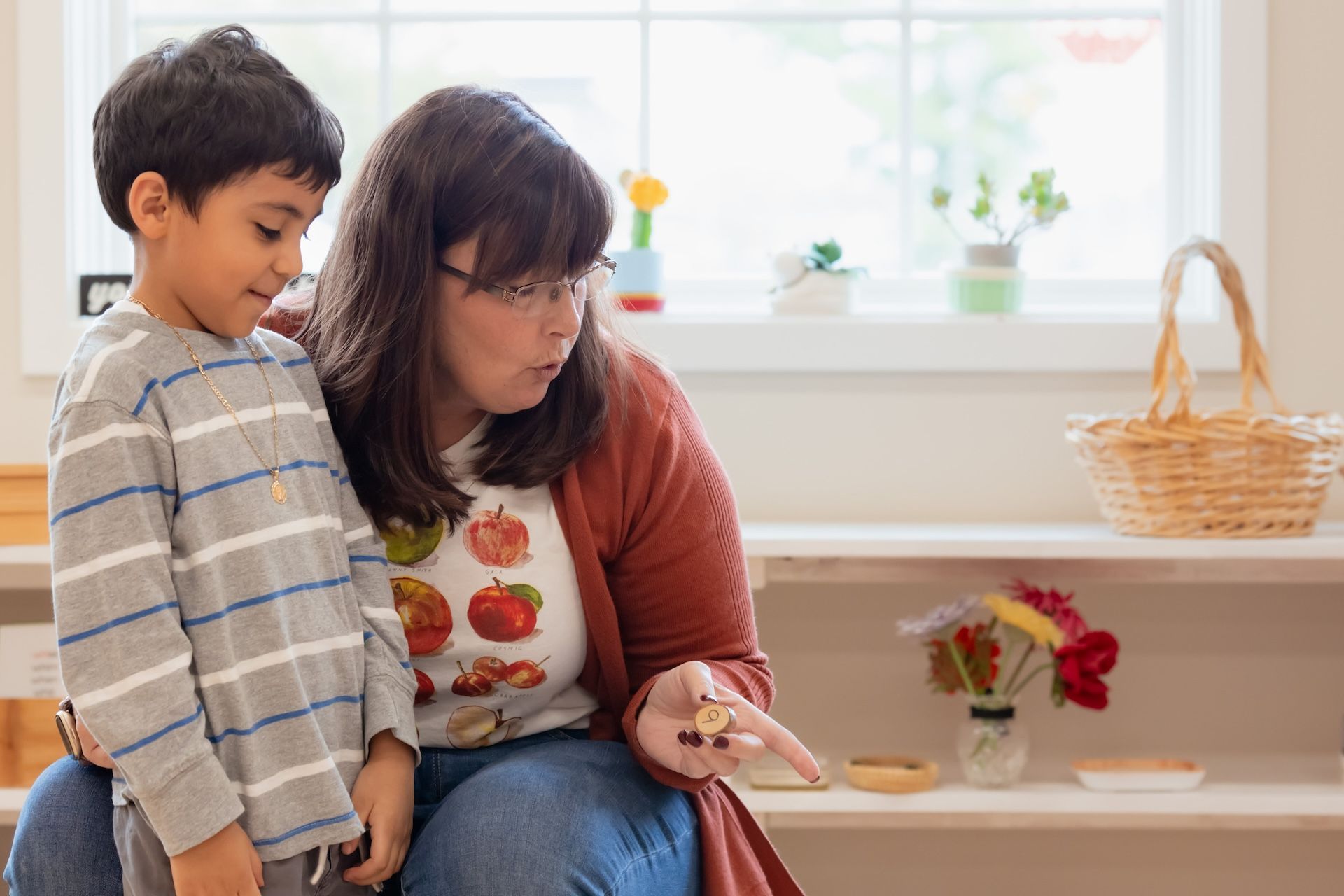 Woman and child looking at small items in a classroom setting.