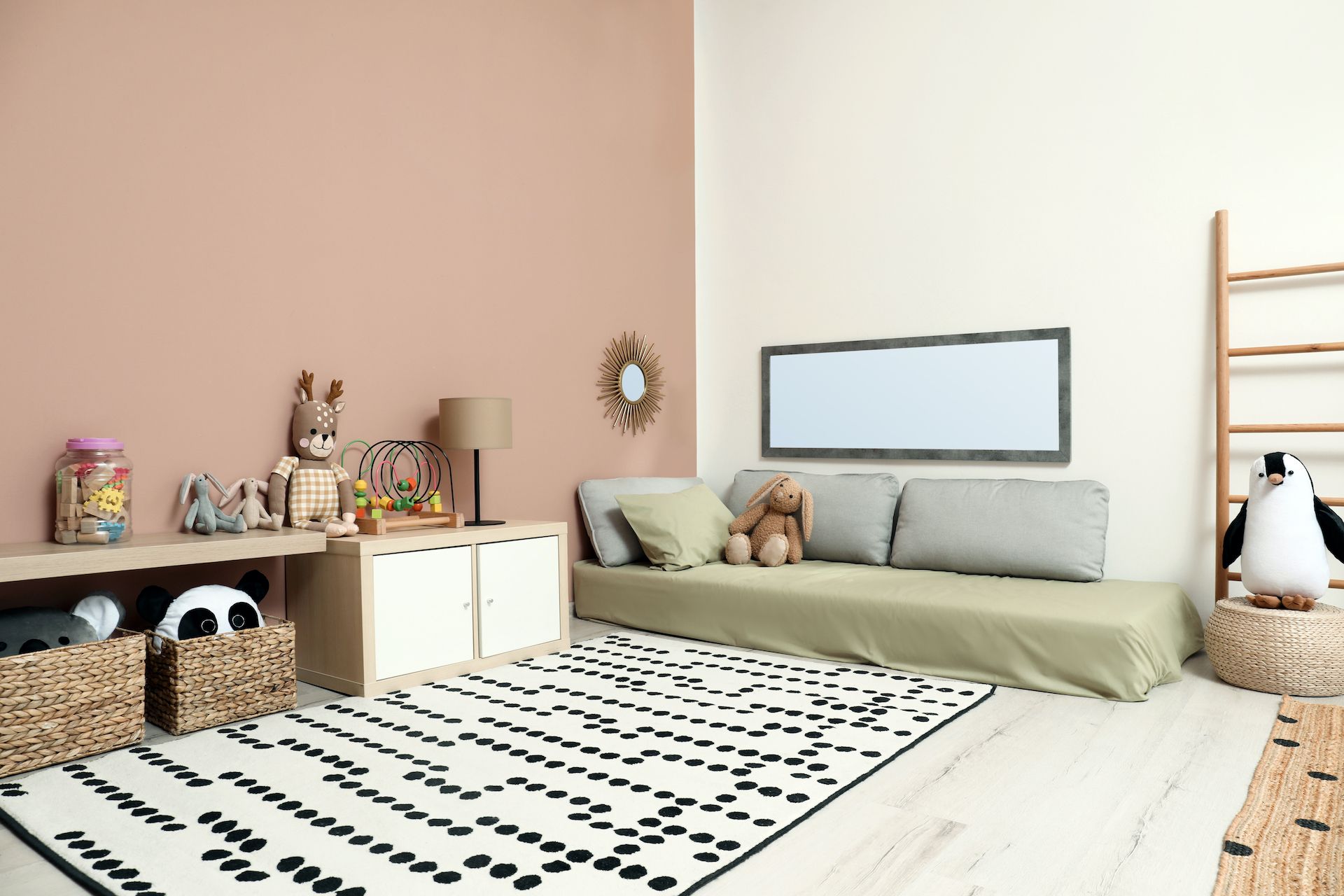 Child's playroom with a couch, rug, toys, and baskets, painted in soft pink and beige colors.