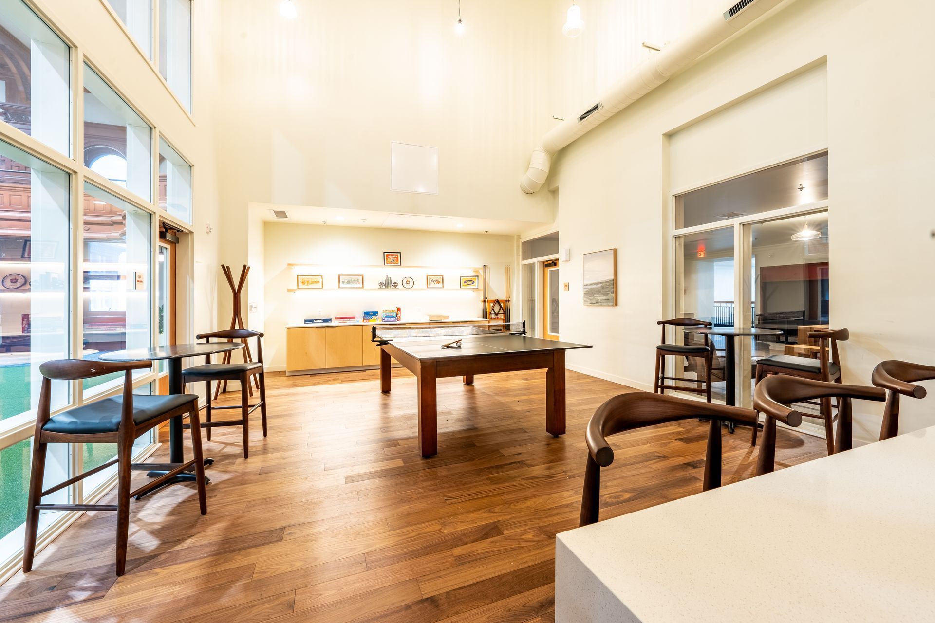 Bright, spacious interior with wooden floors, tall windows, a pool table, and bar seating at Zenith Apartments in Duluth, MN.