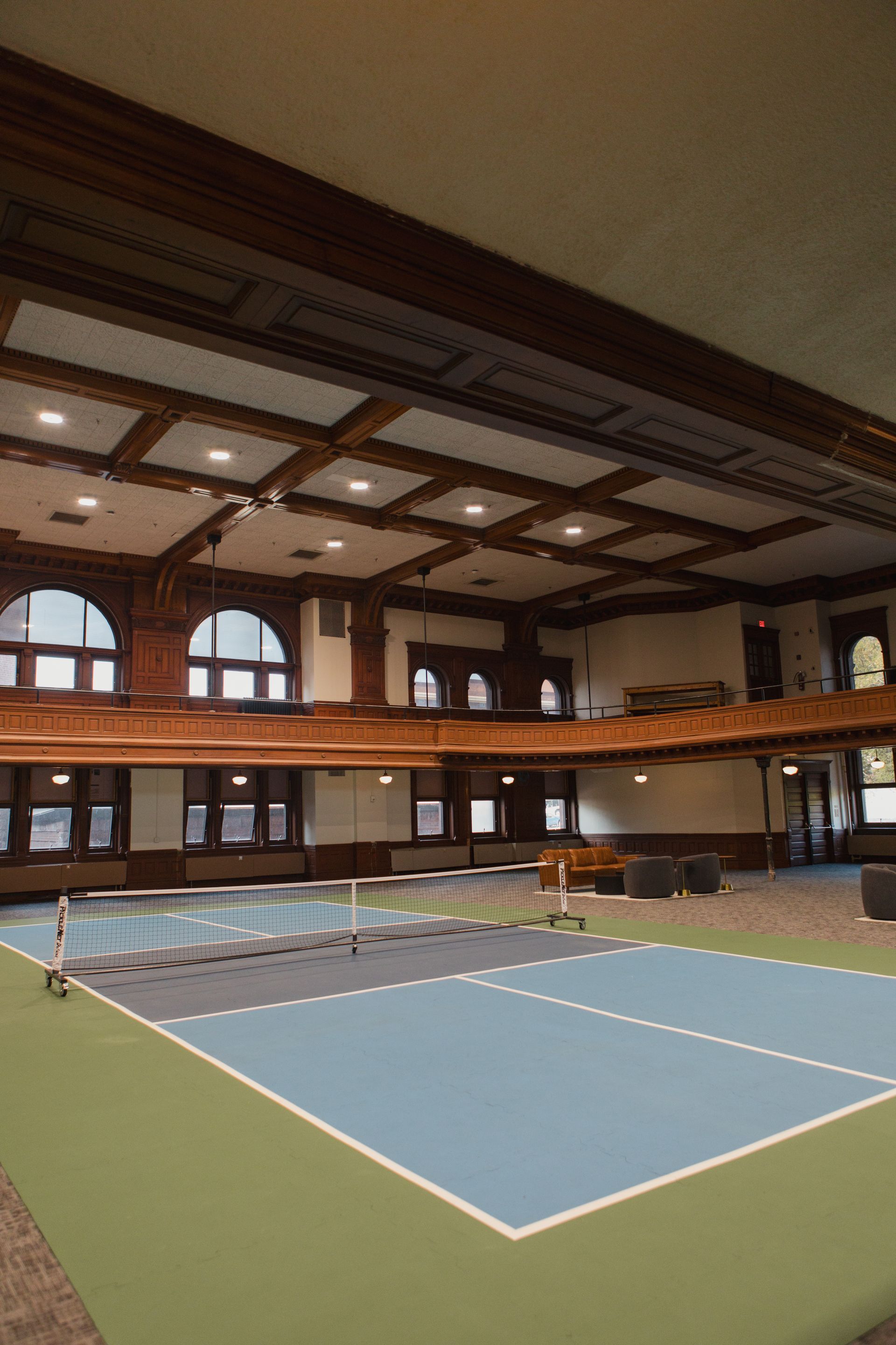 Indoor tennis court with blue and green court, dark wood trim, and a balcony at Zenith Apartments in Duluth, MN.