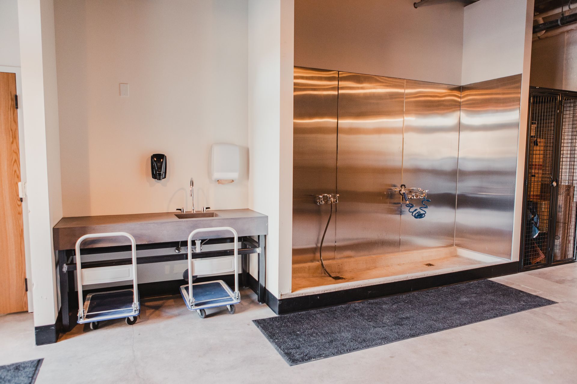 Dog wash station with stainless steel shower, sink, and two small rolling carts at Zenith Apartments in Duluth, MN.