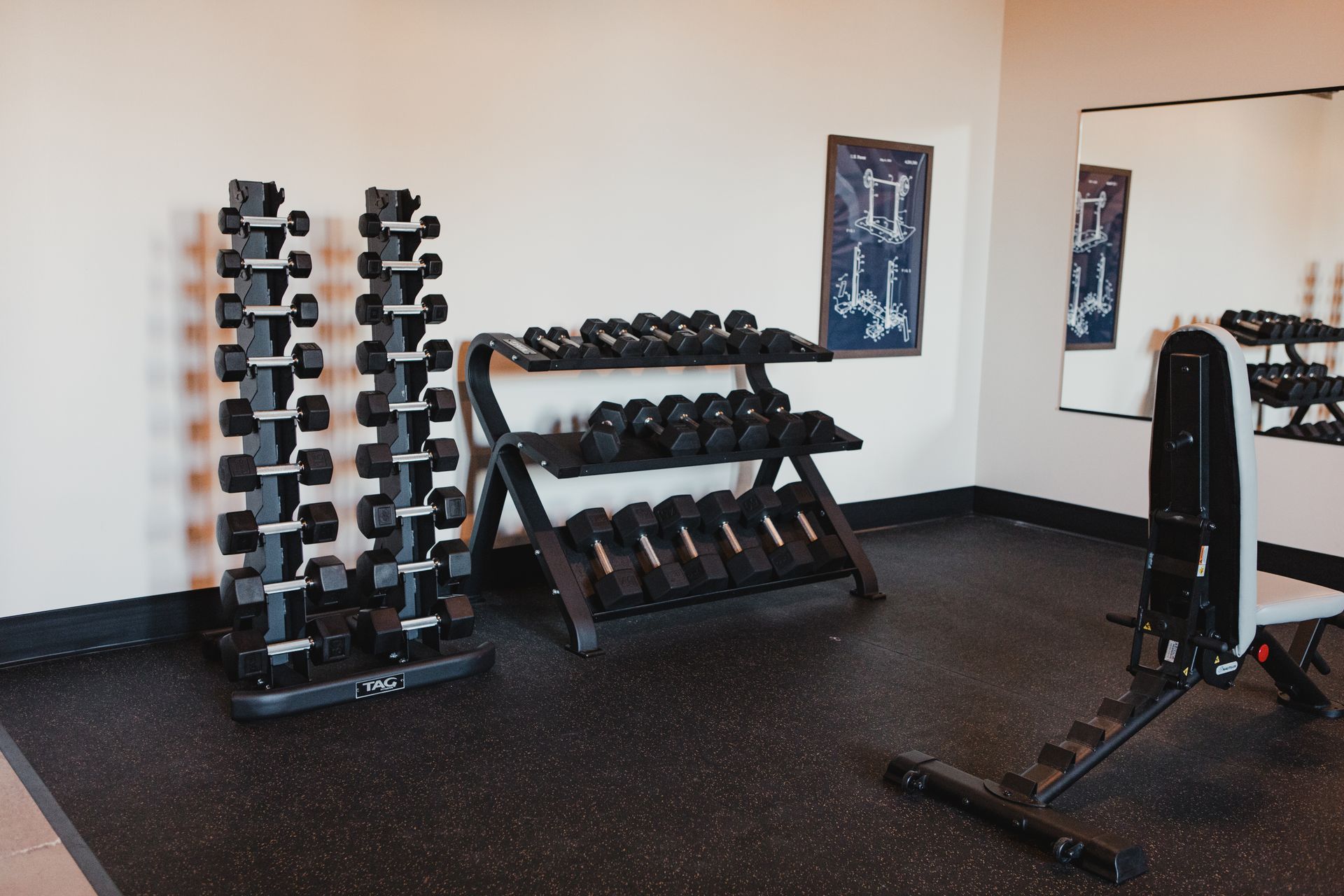 Home gym with dumbbell racks, a weight bench, and a mirror at Zenith Apartments in Duluth, MN.