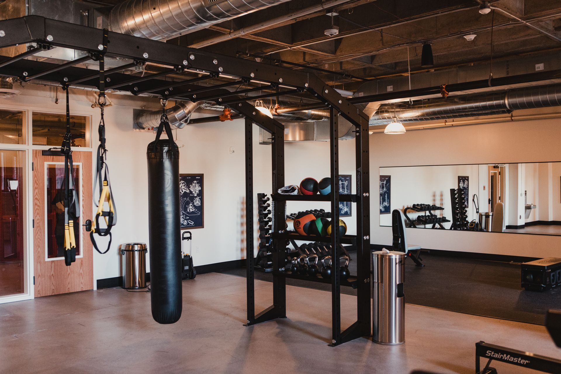Gym interior with exercise equipment: boxing bag, weights, and TRX straps at Zenith Apartments in Duluth, MN.