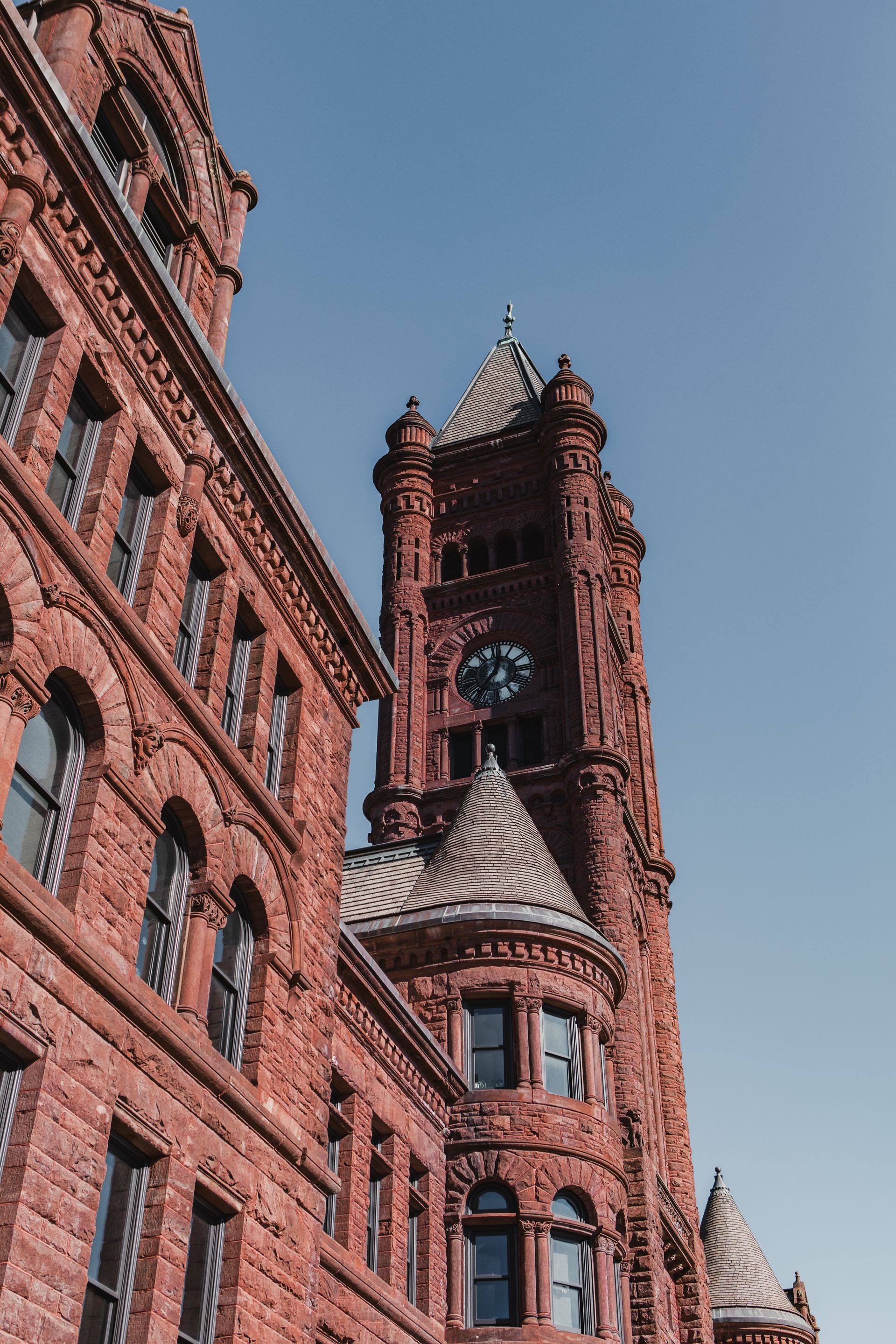 Red brick building with a clock tower against a clear blue sky  at Zenith Apartments in Duluth, MN.