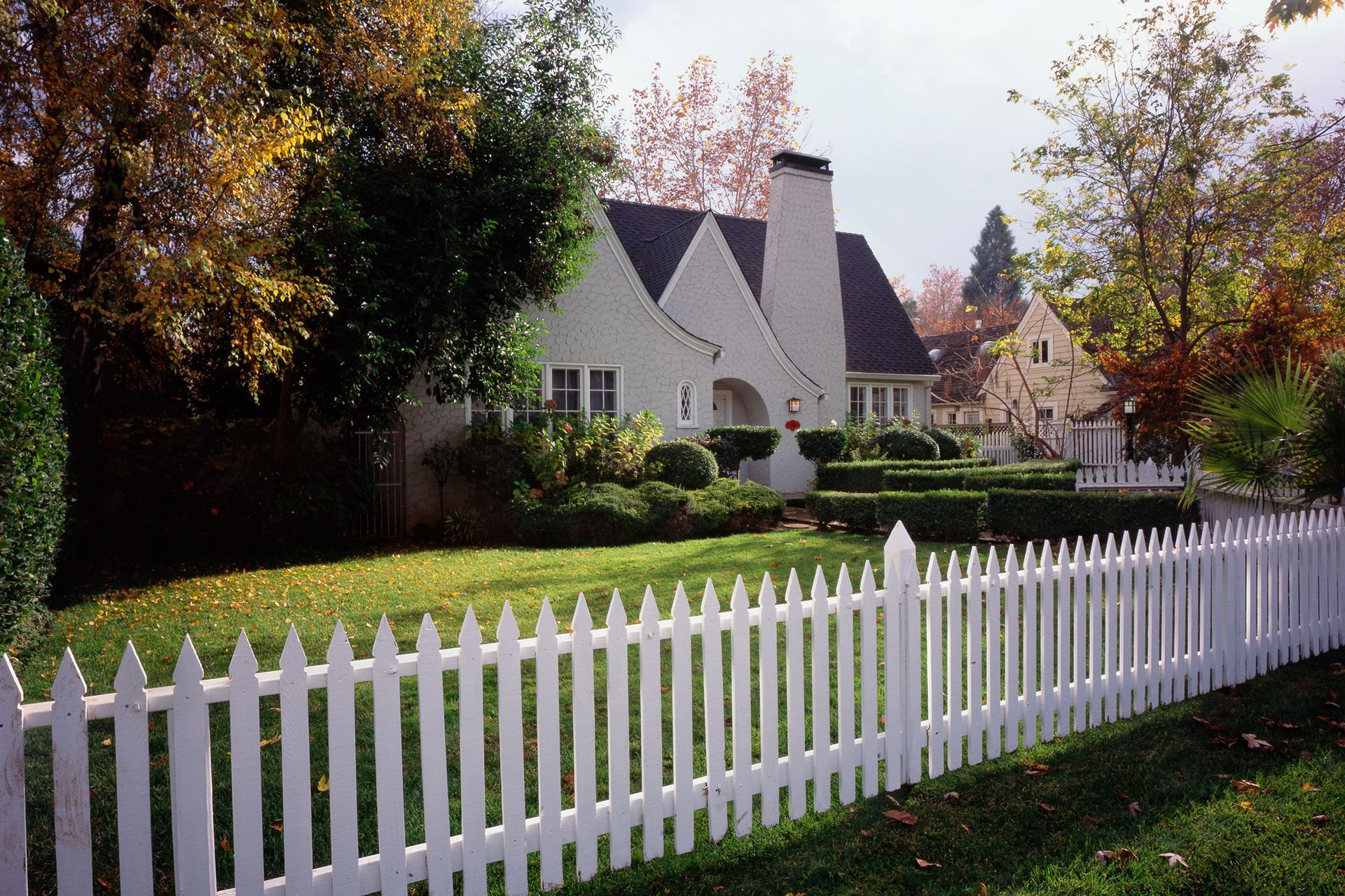 A white picket fence surrounds a white house A white picket fence surrounds a white house