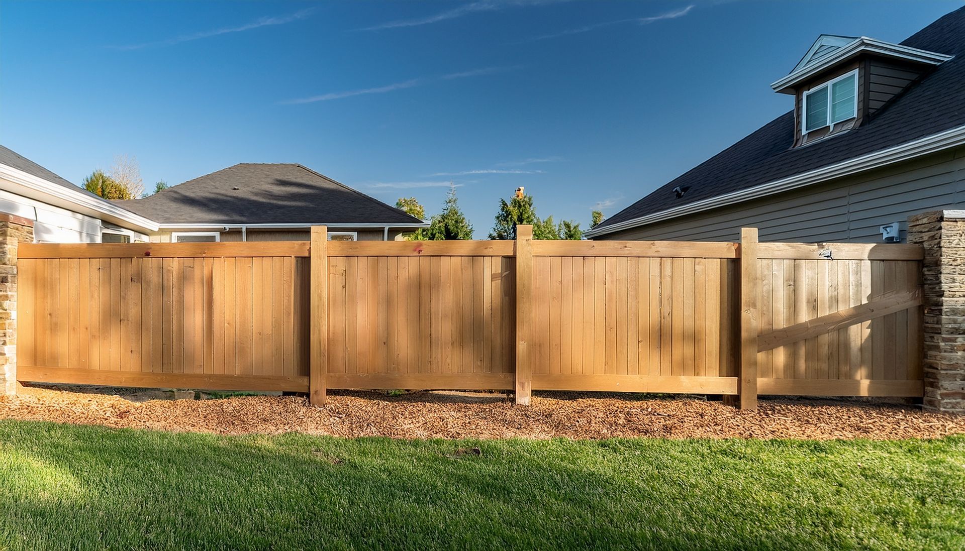 Modern backyard featuring a sturdy new fence installation and fresh brown mulch landscaping.