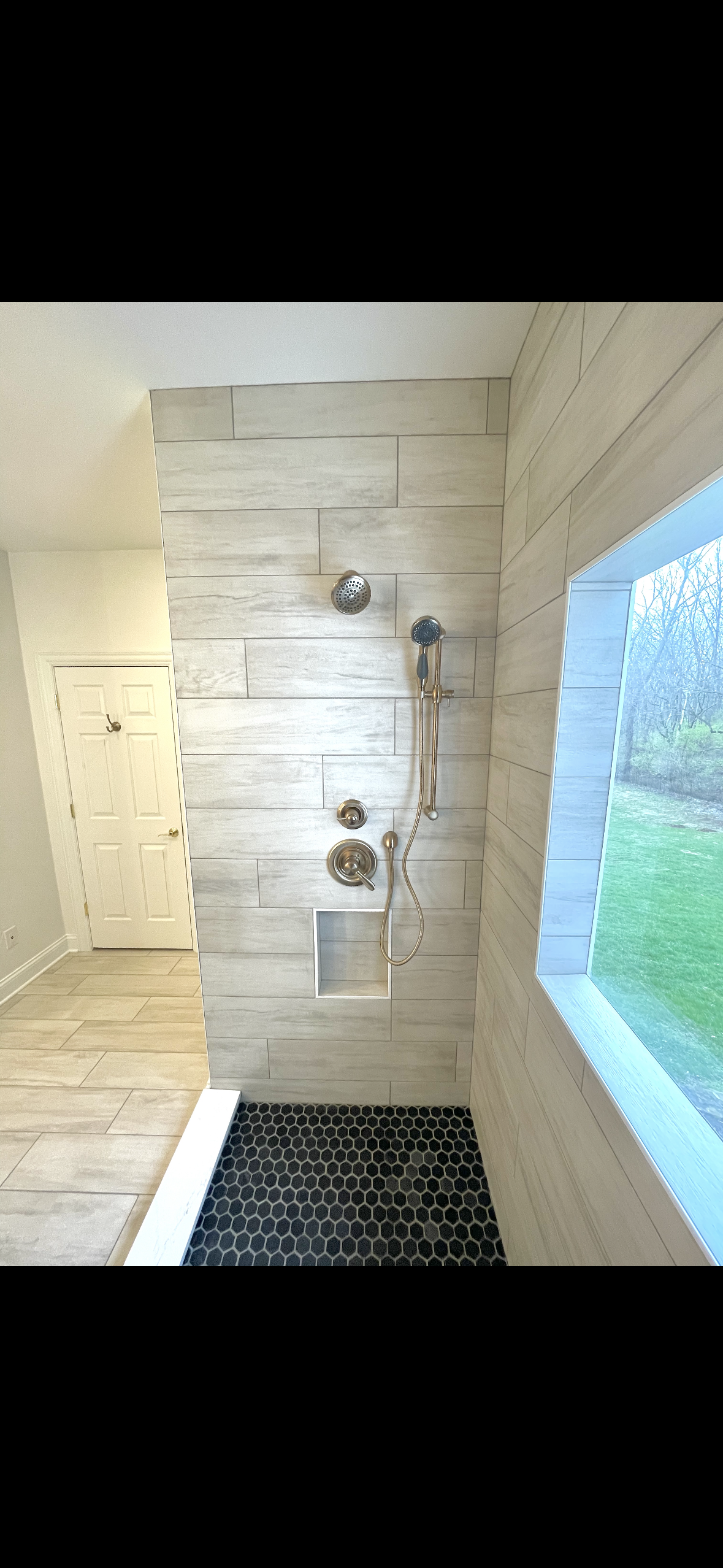 A bathroom with a walk in shower and a window.