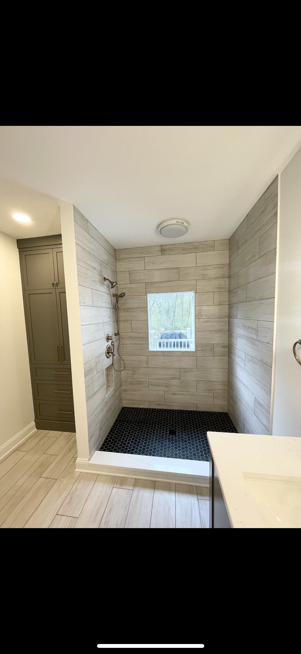 A bathroom with a walk in shower and a window.